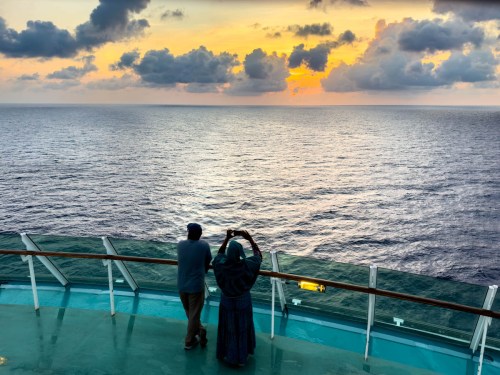 Woman and man watch sunrise from the Independence of the Seas
