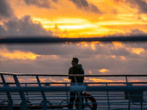 Man in silhouette watches sunrise from Independence of the Seas