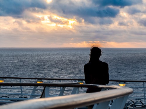 Woman in silhouette watches sunrise on Independence of the Seas